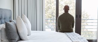 Man sitting on his bed looking out a window