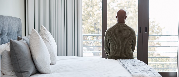 Man sitting on his bed looking out a window