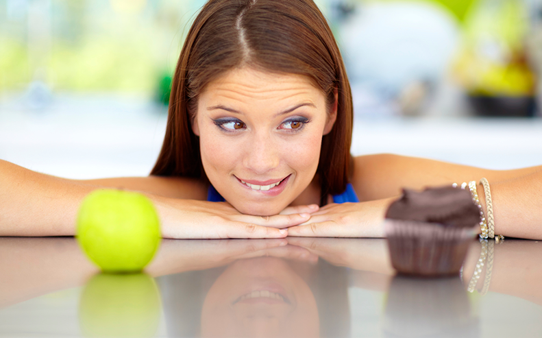woman choosing between apple and cupcake