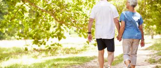 An older couple walks together in a park.