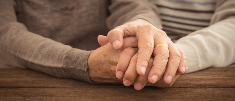 An older couple holds hands.