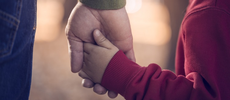 Father and son holding hands in public park