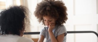 A child looks down, focused on or anxious about a task.