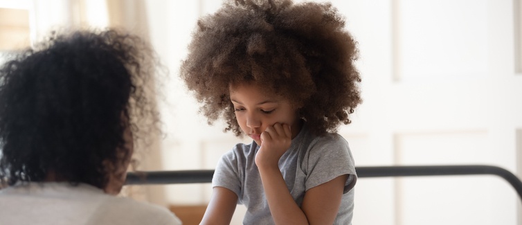 A child looks down, focused on or anxious about a task.