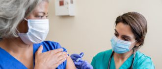 Nurse gives senior adult healthcare worker the Covid-19 vaccine