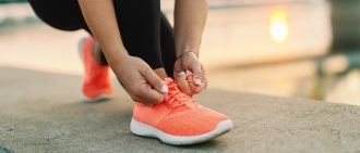 Close up of sporty woman tying shoelace while kneeling outdoor, In background bridge. Fitness outdoors concept.