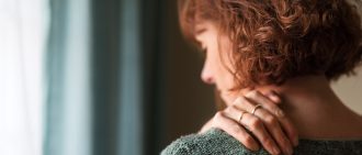 Rear view shot of a woman suffering from shoulder pain.