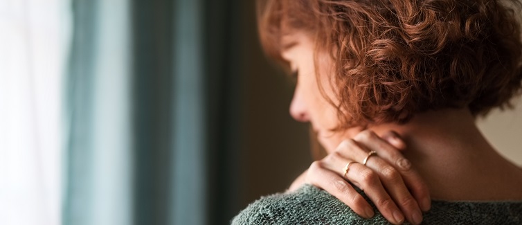 Rear view shot of a woman suffering from shoulder pain.