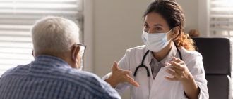 Close up female therapist wearing facemask consulting mature patient.